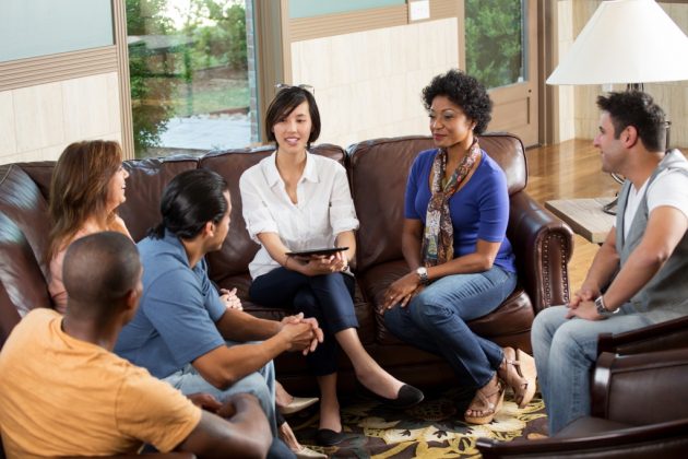 A group meeting with people sitting on couches and talking.